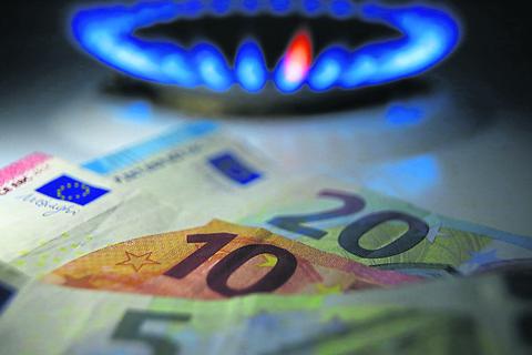 Hinter Euro-Noten brennt an einem Herd eine Gasflamme. Foto: dpa