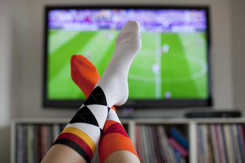 Ein junge Frau trägt am vor einem Fernseher in Köln während eines EM-Spiels Socken in den Deutschlandfarben und in den Farben der Niederlande.
