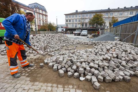 Ein Bauarbeiter setzt letzte Steine ins neue Pflaster auf dem Darmstädter Marktplatz. Foto: Guido Schiek