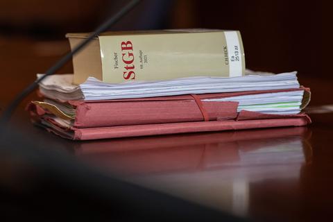 Das Strafgesetzbuch und Akten liegen in einem Gericht auf dem Tisch.