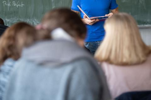 Ein Lehrer steht im Unterricht an der Tafel.