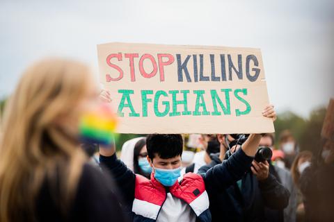Ein Mann hält bei einer Kundgebung für eine schnelle und unbürokratische Evakuierung für bedrohte Menschen aus Afghanistan vor dem Reichstagsgebäude ein Schild mit der Aufschrift "Stop killing Afghans" hoch. Foto: dpa