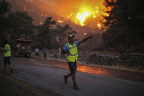 Ein Feuerwehrmann zeigt auf ein Feuer, das im Dorf Cokertme in der Nähe von Bodrum in der Türkei wütet. Foto: dpa