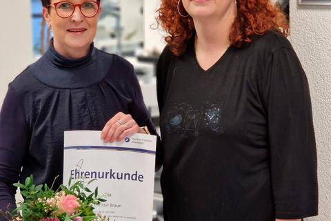 Anke Müller überreicht ihrer langjährigen Mitarbeiterin Christel Braun zum Jubiläum eine Urkunde und einen Strauß Blumen. © Frisurenstudio Houserek