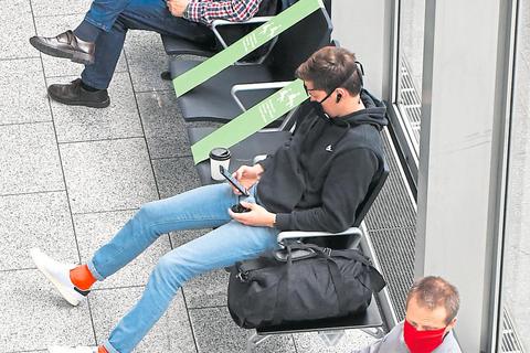Warten mit Abstand: Am Frankfurter Flughafen sind viele Sitzplätze durch grüne Bänder gesperrt, damit sich die wartenden Passagiere nicht zu nahe kommen. 