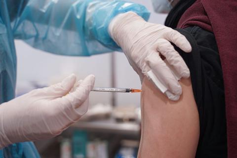 Ein Mitarbeiter eines Impfzentrums impft einen Mann gegen Corona.