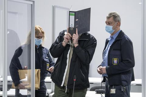 Mit Handschellen wird der Angeklagte in einen provisorischen Verhandlungssaal des Landgerichts Wiesbaden geführt. Die Staatsanwaltschaft wirft dem Mann unter anderem versuchten Mord vor. Foto: dpa