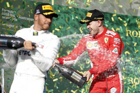 Sebastian Vettel (rechts) vom Team Scuderia Ferrari jubelt mit Champagner über seinen Sieg neben Lewis Hamilton vom Team Mercedes AMG Petronas Motorsport. Foto: dpa 